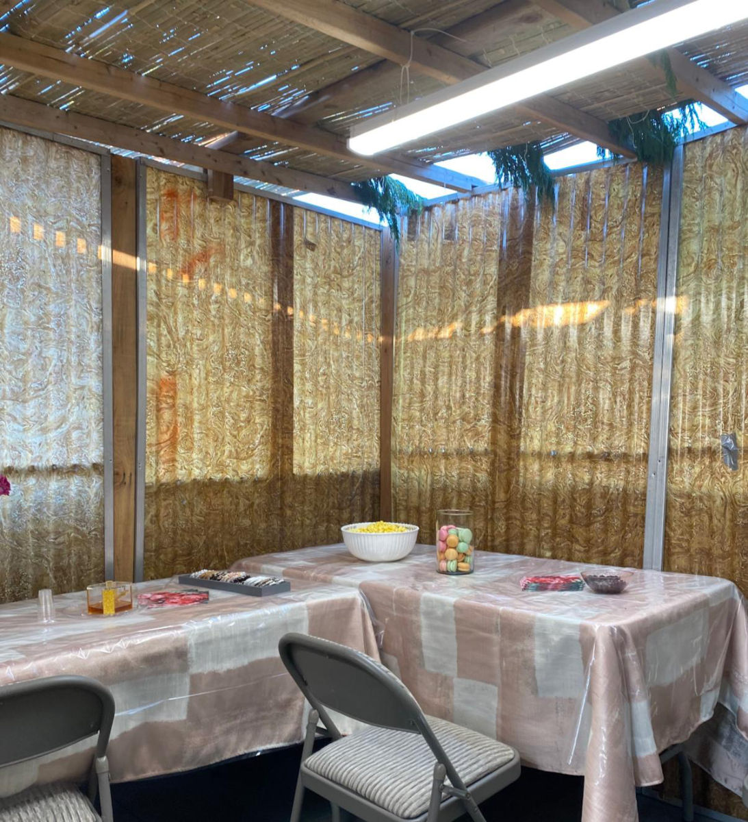 Inside a finished sukkah with schach and tables